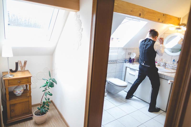 the groom dressing his hair in the bathroom
