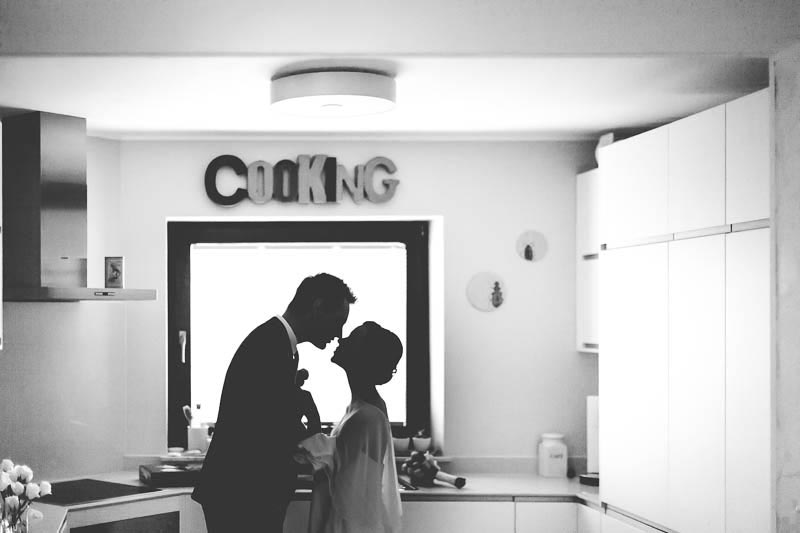 bride and groom kissing in their kitchen