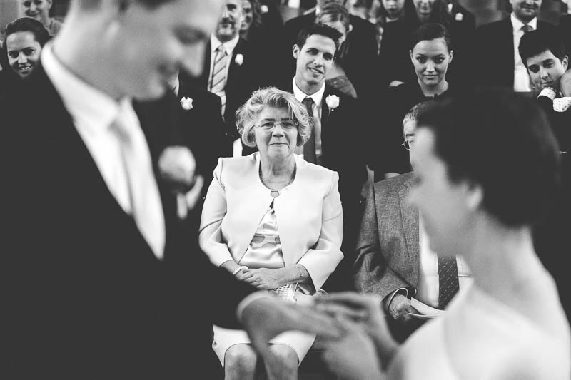 mom breaking in tears while bride puts wedding ring on groom's finger
