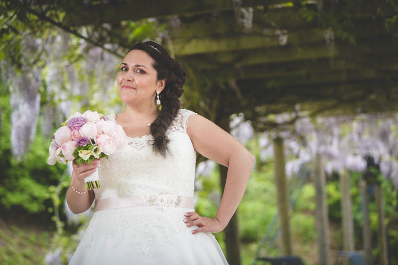 la mariée pose avec son bouqet sous un joli porche
