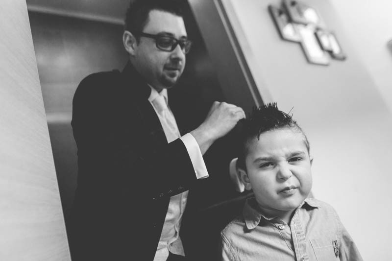 petit garcon grimace pendant que son père le recoiffe