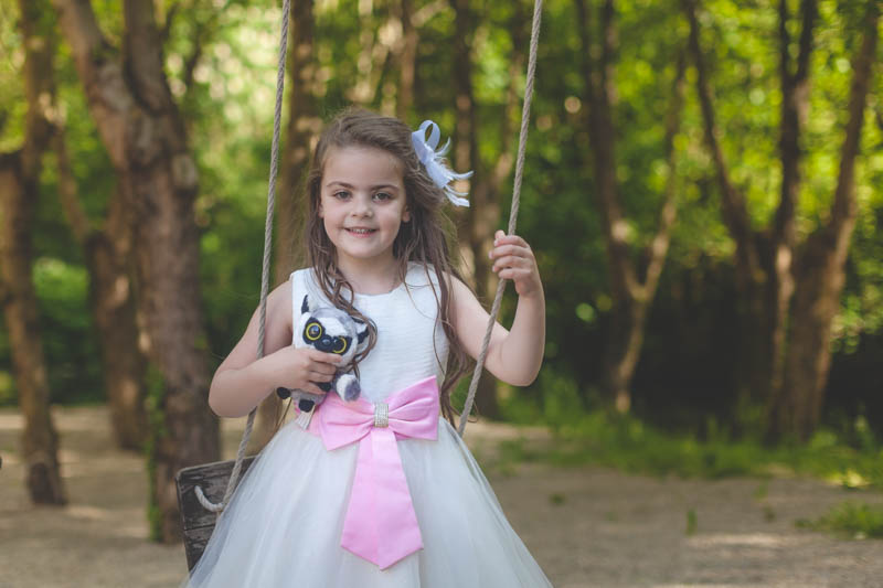a young girl wearing a red-ribbon dress plays with swing