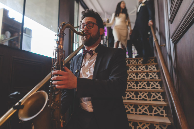 saxophon player leads teh bride and groom to their table