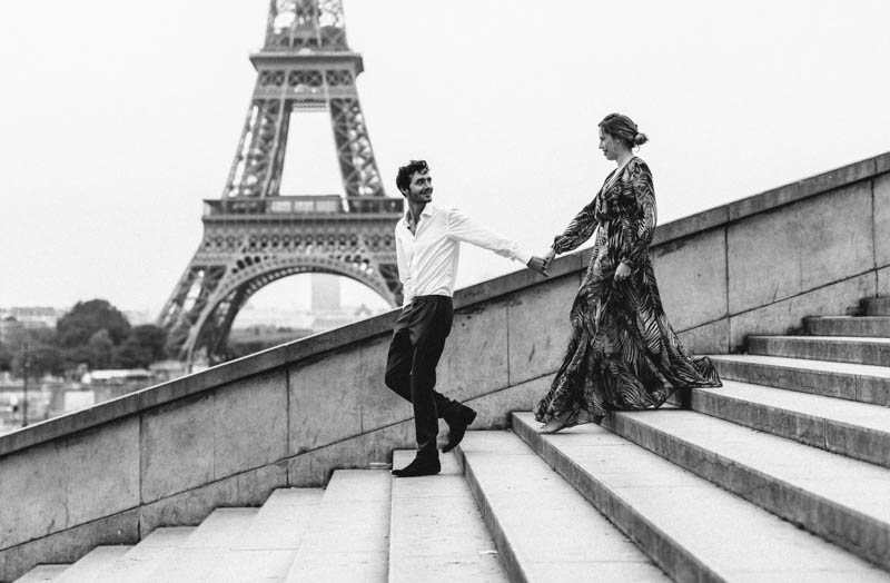 couple qui descend les marches devant la tour eiffel